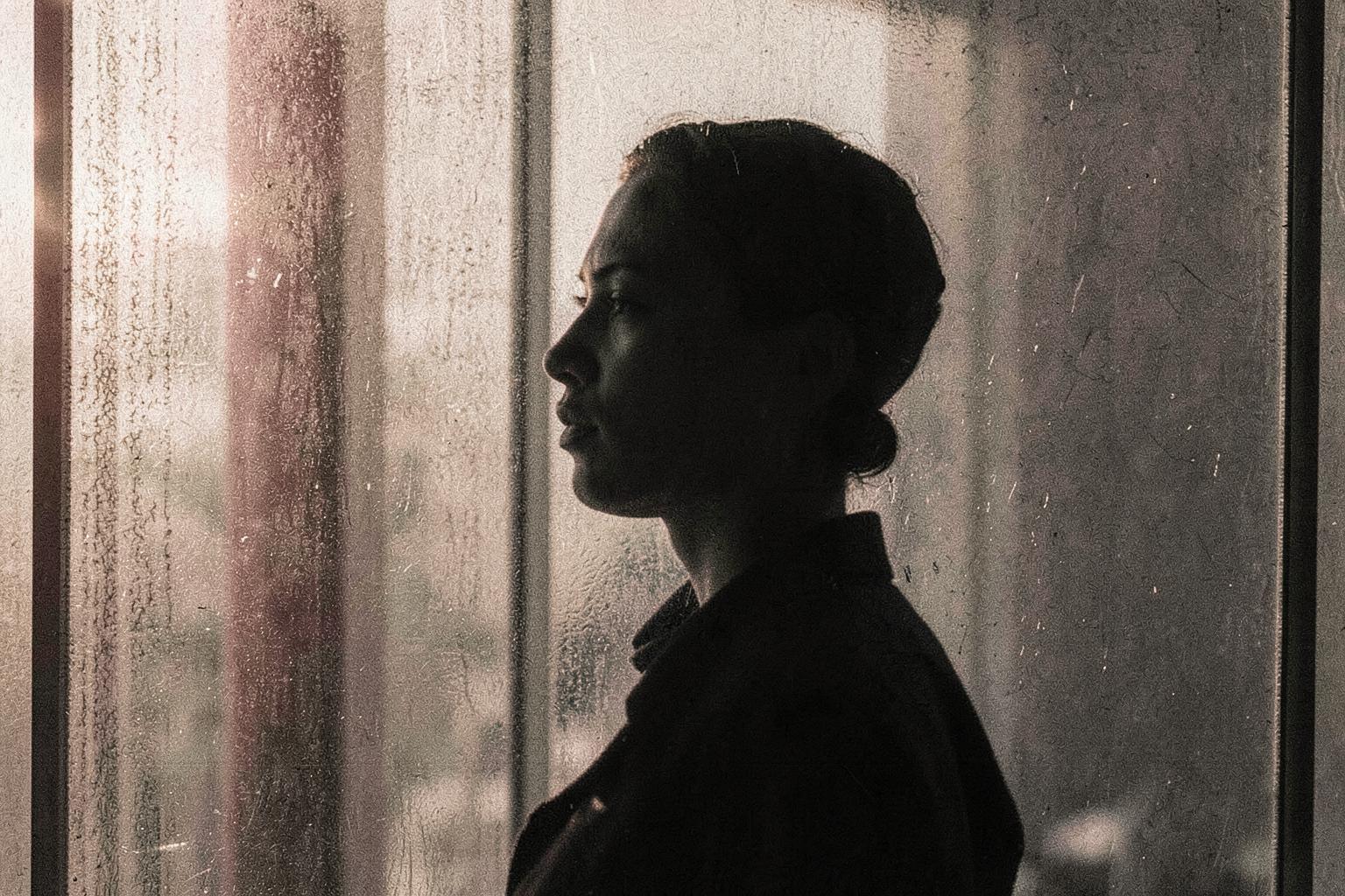 A contemplative figure seen through textured glass